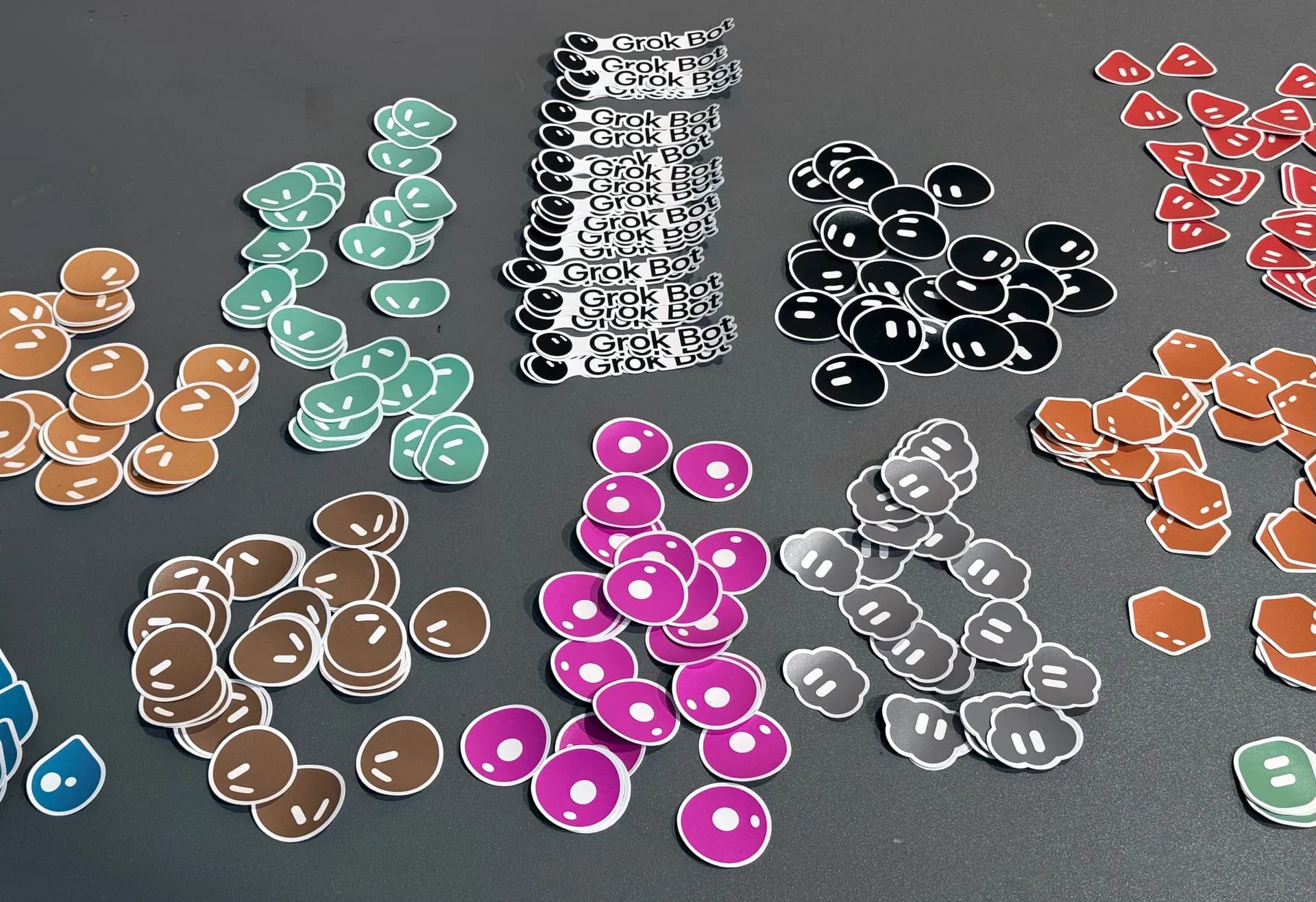 Table covered in piles of colourful Grok Bot stickers