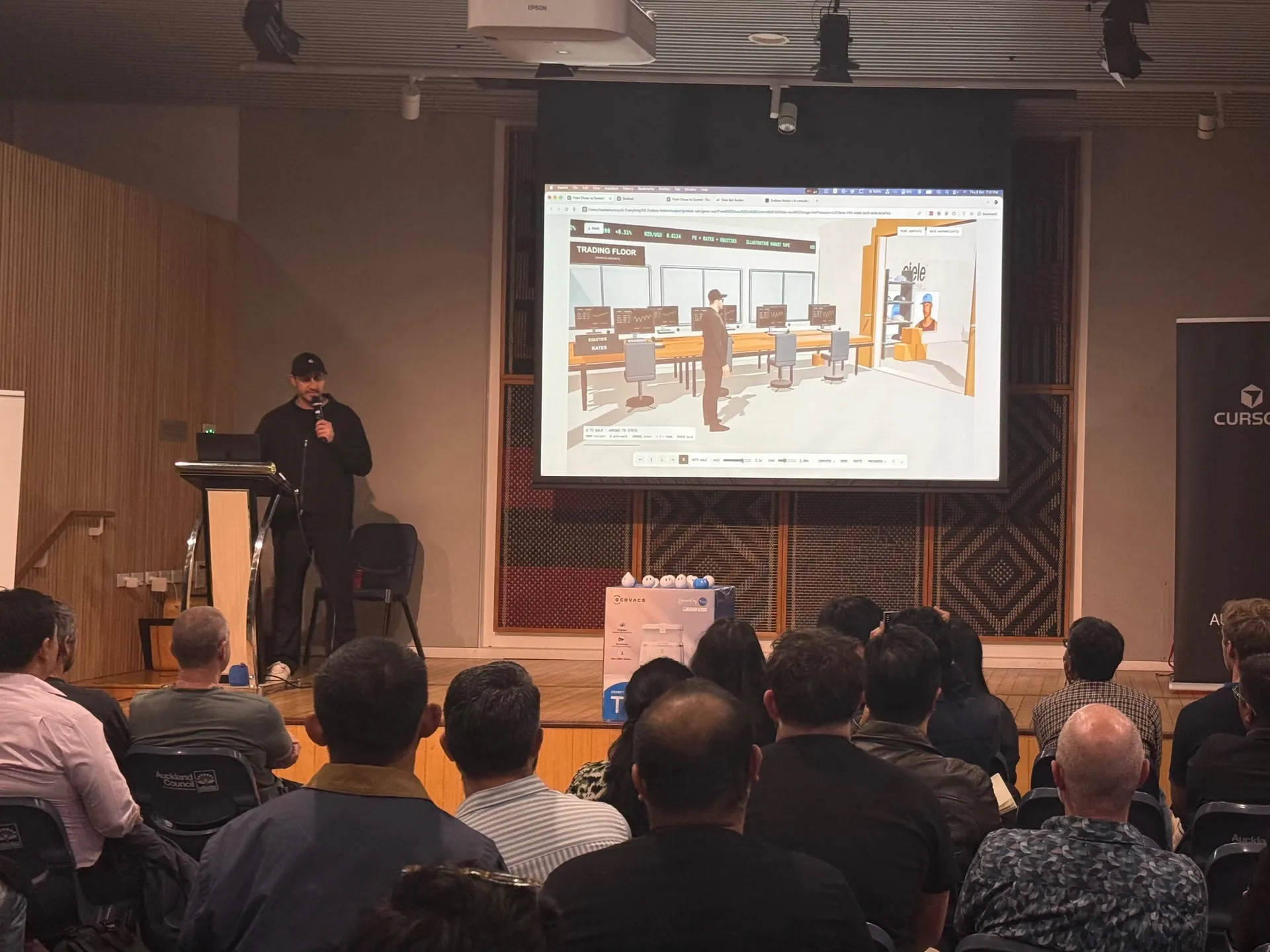 Speaker presenting a 3D office scene on screen