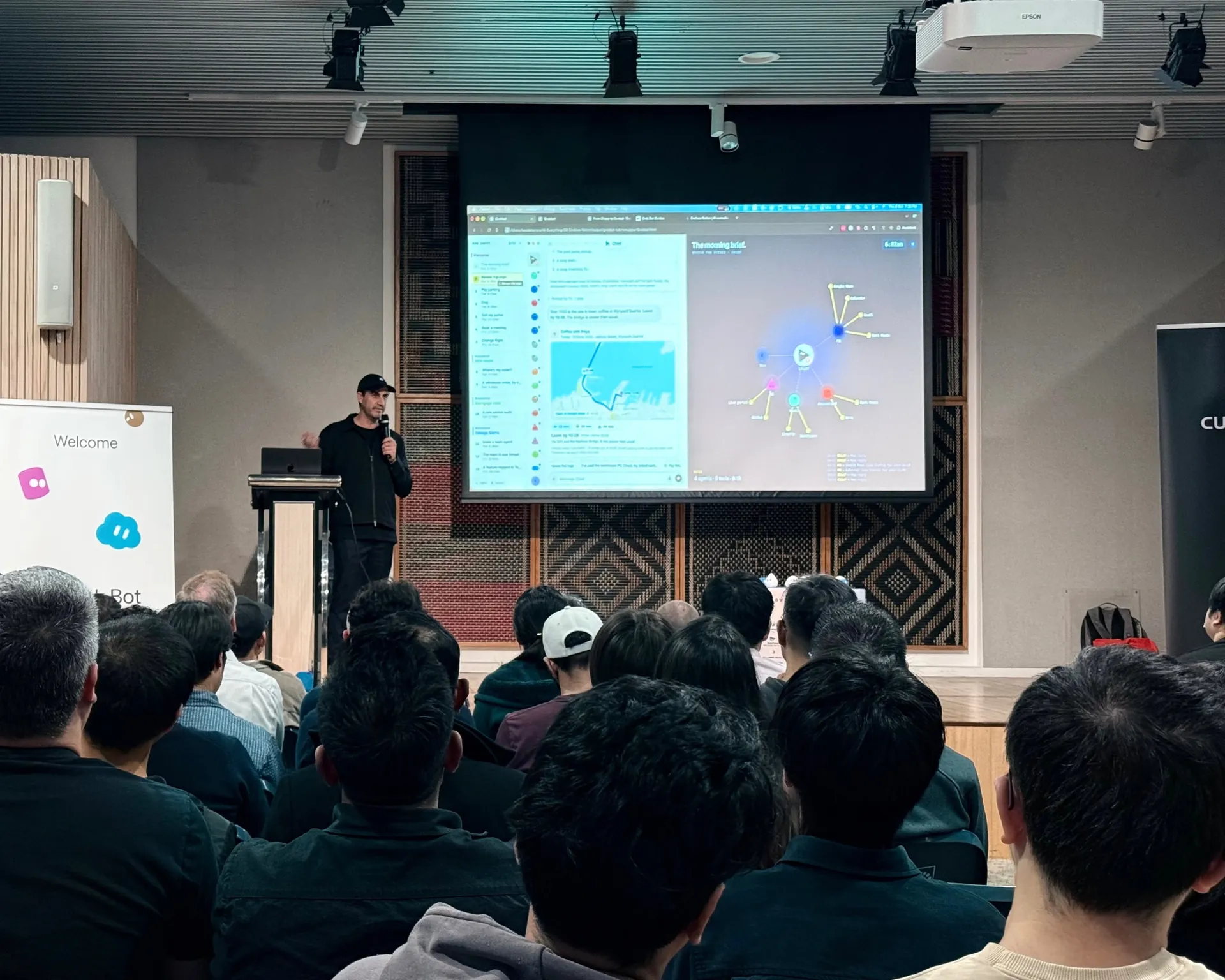 Speaker on stage with a live demo on screen