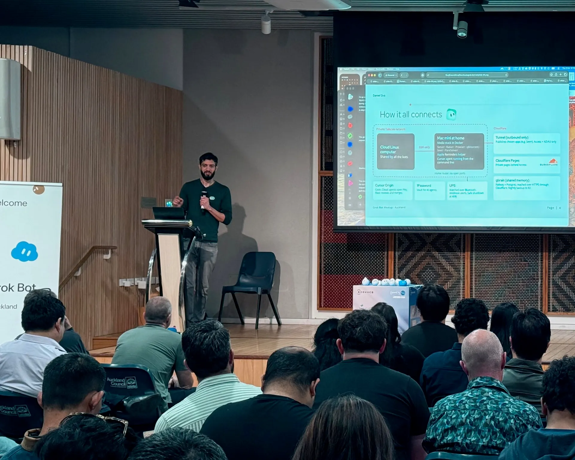 Speaker at the lectern with an architecture diagram on screen