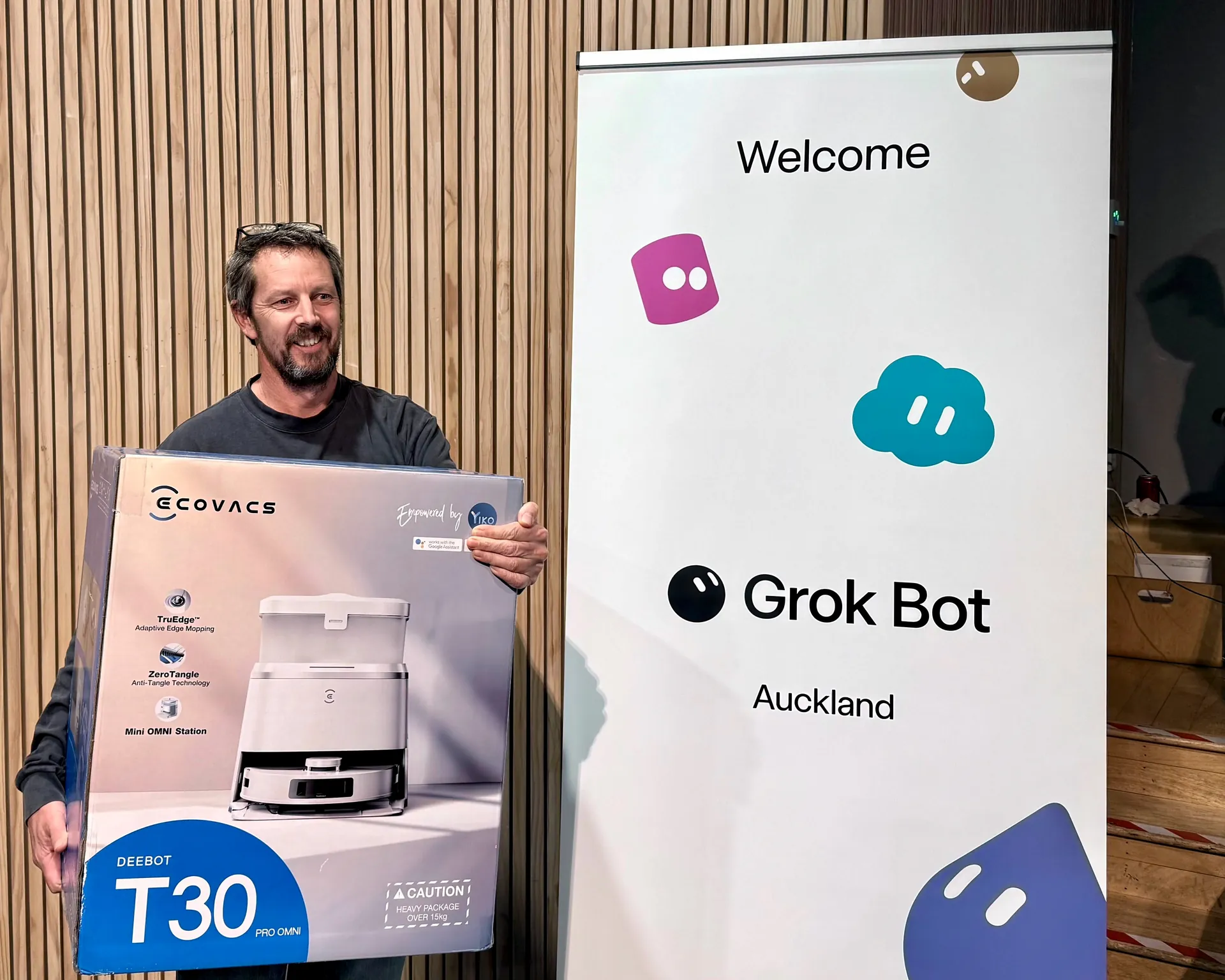 Kahoot winner smiling with the robot vacuum prize beside the Grok Bot welcome banner
