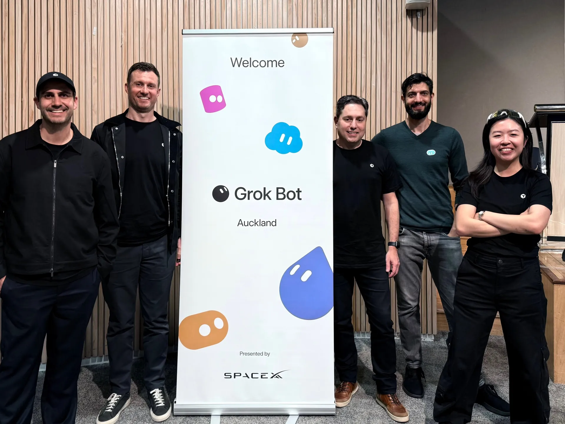 Team photo next to the Grok Bot welcome banner at the end of the night
